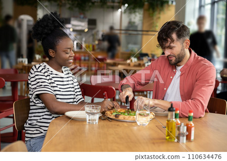 Young couple having pizza in a cafe and looking enjoyed Young couple having pizza in a cafe and looking enjoyed 110634476