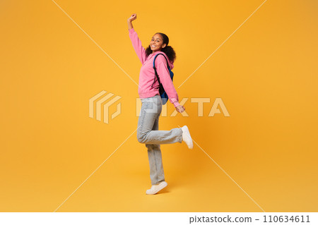 black student girl posing with blue backpack over yellow background 110634611