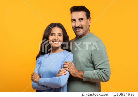 A content couple stands closely, with the man's arm around the woman 110634685