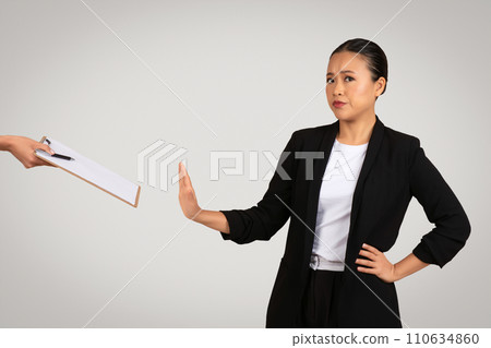 Determined Asian businesswoman in a black suit making a rejecting gesture 110634860