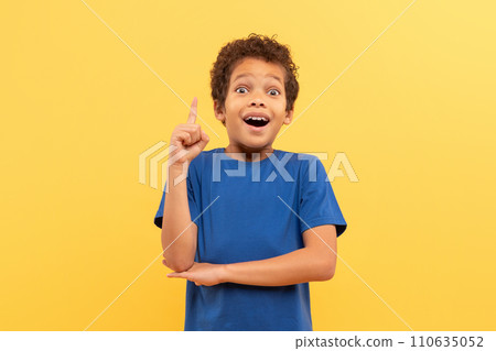 Excited boy with eureka moment, pointing up on yellow background Excited boy with eureka moment, pointing up on yellow background 110635052