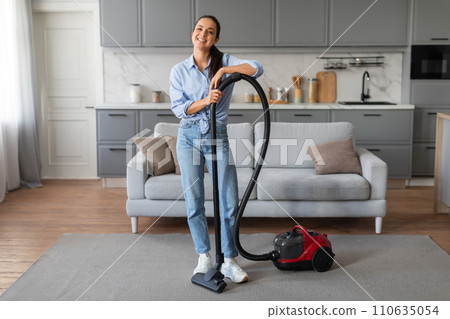 Casual woman vacuuming rug, enjoying chores at home 110635054