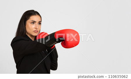 Business success concept. Young caucasian female entrepreneur in boxing gloves making strike, copy space, panorama 110635062