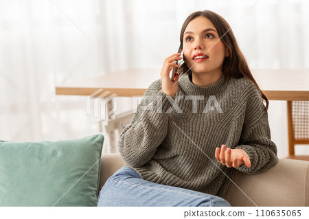 Cheerful pretty young woman have phone conversation at home 110635065