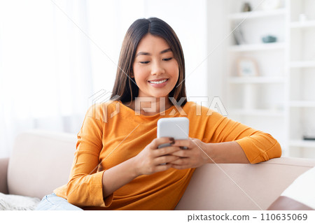 Closeup candid photo of young pretty asian lady using smartphone 110635069