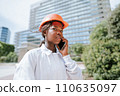 Serious black woman in helmet talking on smartphone in daylight 110635097