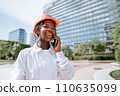 Happy black woman in helmet talking on smartphone in daylight 110635099