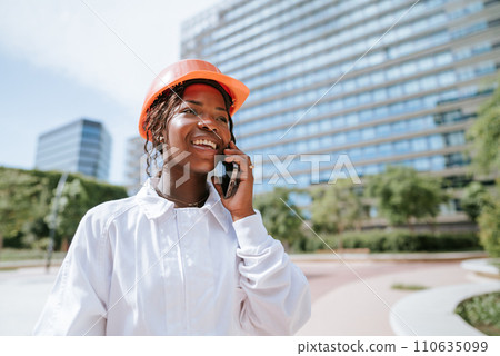 Happy black woman in helmet talking on smartphone in daylight Happy black woman in helmet talking on smartphone in daylight 110635099