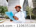 Professional female engineer in hardhat reading documents 110635108
