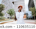 Happy black woman in helmet standing with coffee cup and speaking on smartphone 110635110