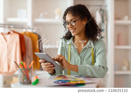 Smiling latin fashion designer with digital tablet and color chart in studio Smiling latin fashion designer with digital tablet and color chart in studio 110635132