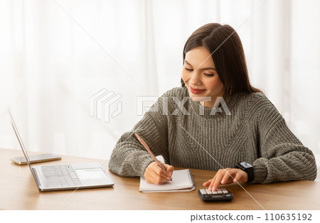 Cheerful young woman counting her monthly spendings 110635192