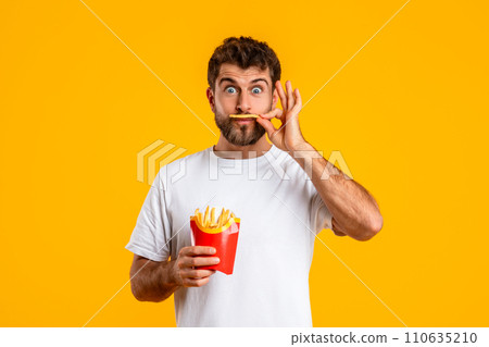 Funny Hungry Man Tasting French Fries Posing Over Yellow Background 110635210