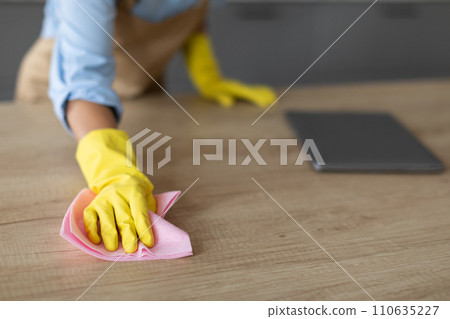 Closeup of hand in yellow glove cleaning with cloth 110635227