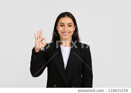 Cheerful european businesswoman giving an OK hand gesture to signify approval or success 110635250
