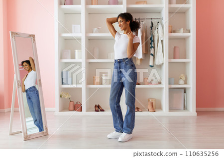 Confident latin woman posing in jeans, admiring mirror image 110635256