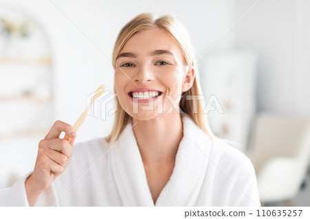European blonde woman maintaining oral health brushing teeth in bathroom European blonde woman maintaining oral health brushing teeth in bathroom 110635257