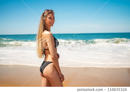 Beautiful young woman in bikini enjoying beach 110635326