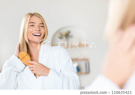 blonde lady brushing strong long hair at her home bathroom blonde lady brushing strong long hair at her home bathroom 110635421