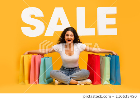 indian woman sitting with purchases over yellow background word SALE indian woman sitting with purchases over yellow background word SALE 110635450
