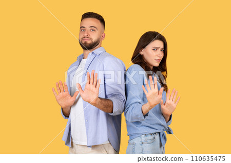 Couple gesturing stop with hands, standoffish poses, yellow background Couple gesturing stop with hands, standoffish poses, yellow background 110635475
