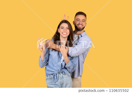 Playful couple with woman showing peace sign, man behind 110635502