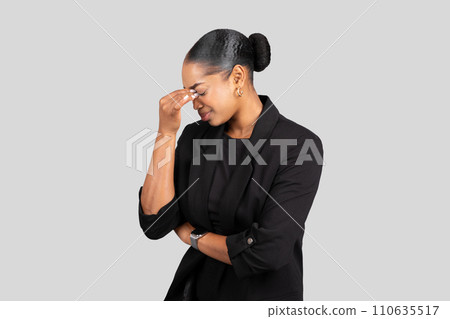 A young woman in a black blazer touches her temple in a gesture of contemplation 110635517