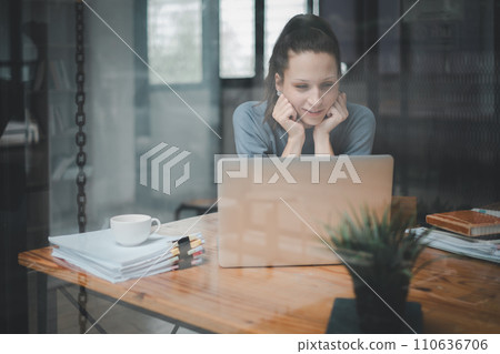 Smiling young woman using laptop computer to calculate financial report, working at office with laptop computer on table. Smiling young woman using laptop computer to calculate financial report, working at office with laptop computer on table. 110636706