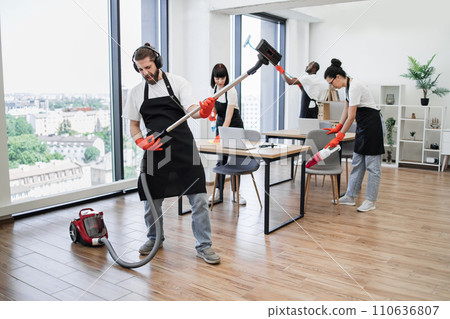 Professional cleaner Caucasian man having fun holding vacuum cleaner like guitar 110636807