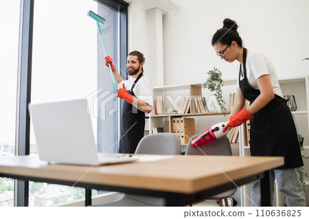 Caucasian worker in a black apron cleaning panoramic window. Caucasian worker in a black apron cleaning panoramic window. 110636825