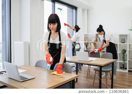 Caucasian young woman holding sponge and detergent cleaning on table in office. 110636861