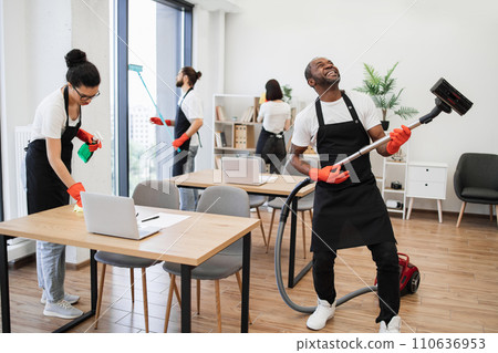 African man having fun holding vacuum cleaner like guitar at concert. 110636953