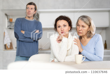 Senior woman sits near daughter and comforts during quarrel with husband 110637646