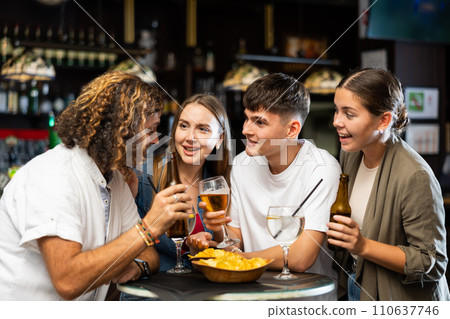Cheerful adult friends talking and drinking beer at table in pub Cheerful adult friends talking and drinking beer at table in pub 110637746