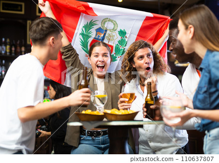Excited multiracial fans with flag of Peru with pint of beer and snacks in the pub Excited multiracial fans with flag of Peru with pint of beer and snacks in the pub 110637807