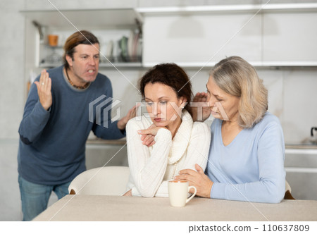 Senior woman sits near daughter and comforts during quarrel with husband Senior woman sits near daughter and comforts during quarrel with husband 110637809