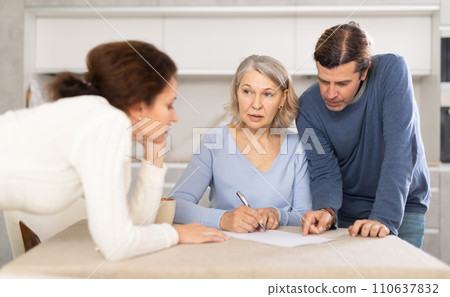 Man and woman help elderly mother make will and fill out document correctly. Man and woman help elderly mother make will and fill out document correctly. 110637832