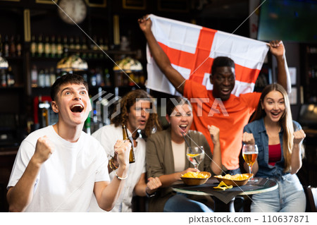 Males and females with England flag clinking glasses with beer on party in bar 110637871
