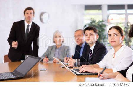 Young businesswoman listening to presentation of partners in office 110637872
