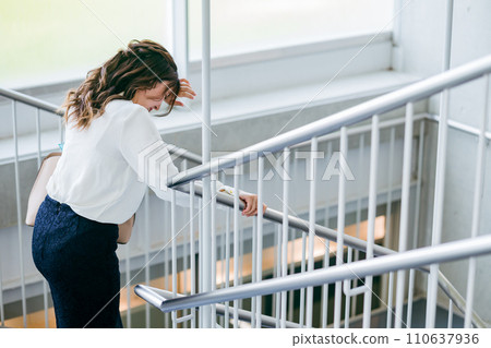 Business woman exhausted after going down the stairs (evacuation, sweat, disaster, emergency stairs) 110637936