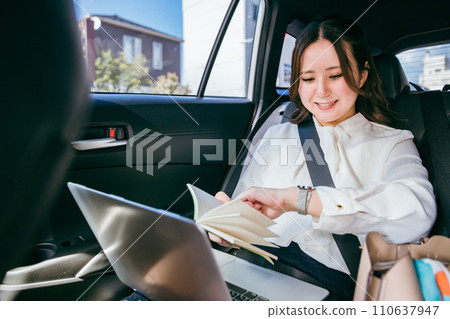 亞洲女商人在汽車後座檢查日程時間（承諾、繁忙日程、時間） 110637947
