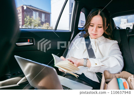 亞洲女商人在計程車上檢查時間表（承諾、忙碌、遲到） 110637948