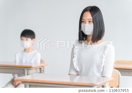 Elementary school students attending class while wearing masks in a school classroom 110637955