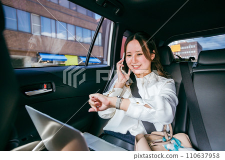 女商人在計程車後座檢查預定時間(預約/電話/時間表) 女商人在計程車後座檢查預定時間(預約/電話/時間表) 110637958