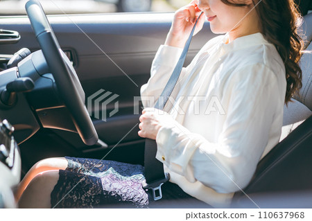 Female driver getting into a car and wearing a seatbelt (traffic rules, safe driving, traffic safety) Female driver getting into a car and wearing a seatbelt (traffic rules, safe driving, traffic safety) 110637968