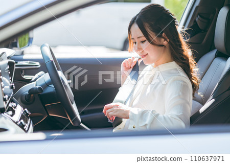Female driver getting into a car and wearing a seatbelt (traffic rules, safe driving, traffic safety) Female driver getting into a car and wearing a seatbelt (traffic rules, safe driving, traffic safety) 110637971