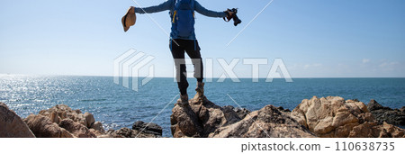 Woman photographer enjoy the view on sunrise seaside rocks Woman photographer enjoy the view on sunrise seaside rocks 110638735