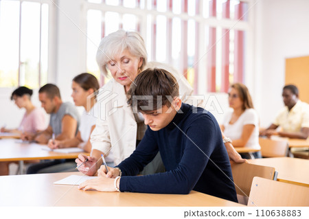 Elderly female teacher helping student solve problem, pointing out error Elderly female teacher helping student solve problem, pointing out error 110638883