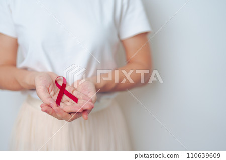 woman with Burgundy Red Ribbon for March multiple myeloma Cancer and December World Aids Day Awareness month. Healthcare and world cancer day concept 110639609