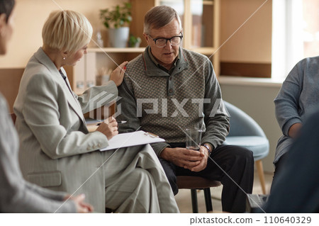 Portrait of senior man sharing mental health struggles with female psychologist in therapy session and holding glass of water, copy space Portrait of senior man sharing mental health struggles with female psychologist in therapy session and holding glass of water, copy space 110640329